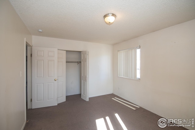 unfurnished bedroom with a textured ceiling, a closet, carpet, and baseboards