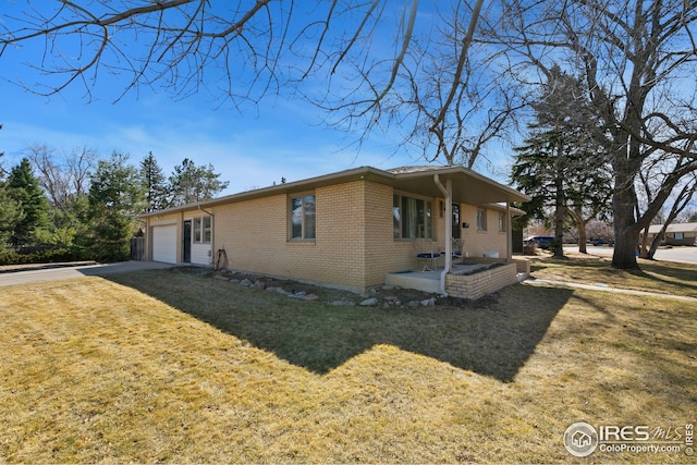 view of side of home with a garage, concrete driveway, brick siding, and a lawn