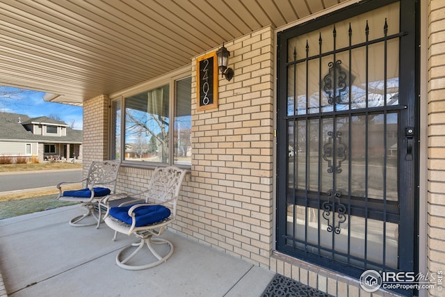 doorway to property with a porch and brick siding