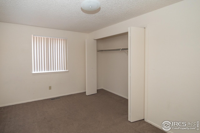 unfurnished bedroom featuring a textured ceiling, a closet, carpet flooring, and baseboards