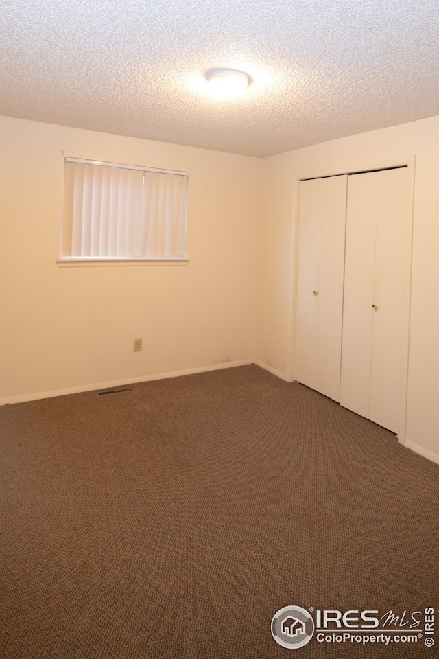 unfurnished bedroom featuring carpet floors, a textured ceiling, baseboards, and a closet