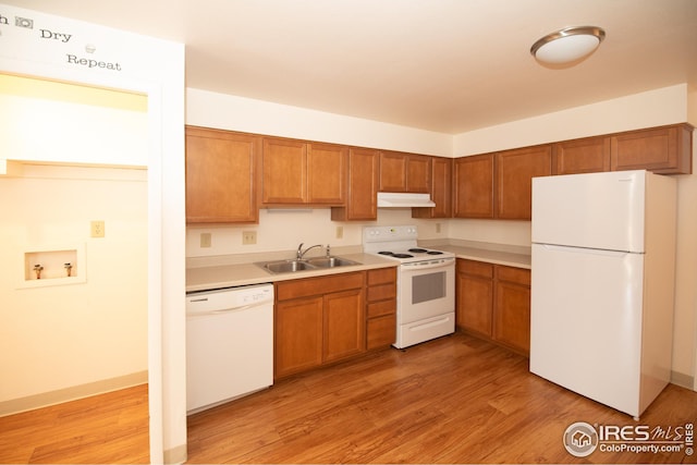 kitchen featuring white appliances, a sink, under cabinet range hood, and light wood finished floors