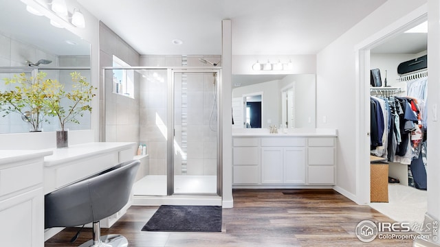 full bath with wood finished floors, a shower stall, vanity, and a walk in closet