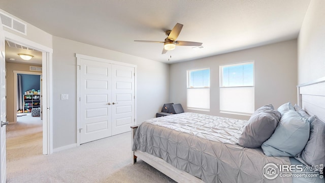 bedroom with a closet, visible vents, ceiling fan, and light carpet