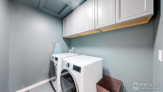 clothes washing area with washer and dryer, cabinet space, and baseboards