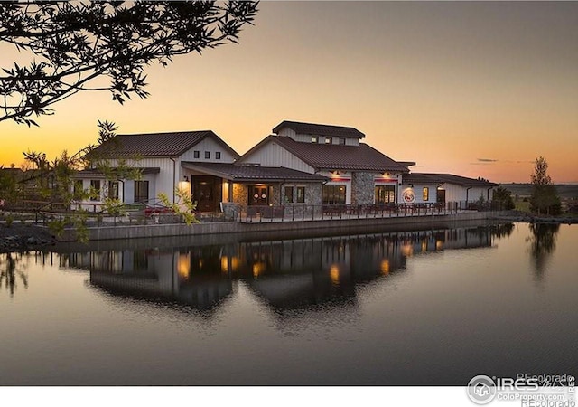 back of house at dusk featuring a water view