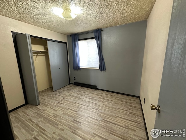 unfurnished bedroom featuring light wood-type flooring, a closet, baseboards, and a textured ceiling