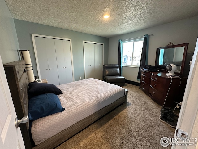 carpeted bedroom featuring a textured ceiling and two closets