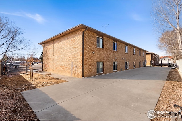 view of side of property with brick siding and fence