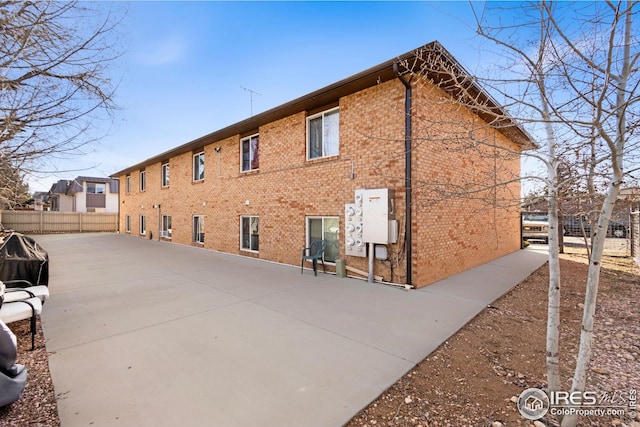 exterior space with brick siding, a patio, and fence