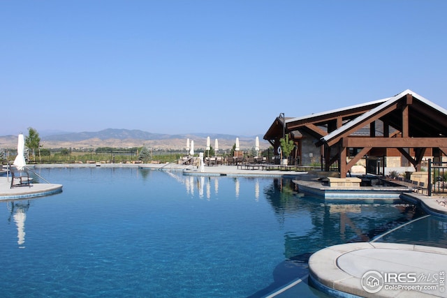 pool with a gazebo, a patio, and a water and mountain view