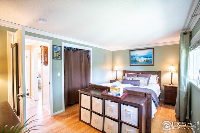 bedroom with light wood-style flooring and crown molding