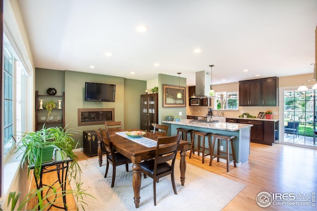 dining space featuring light wood-type flooring, a glass covered fireplace, and recessed lighting