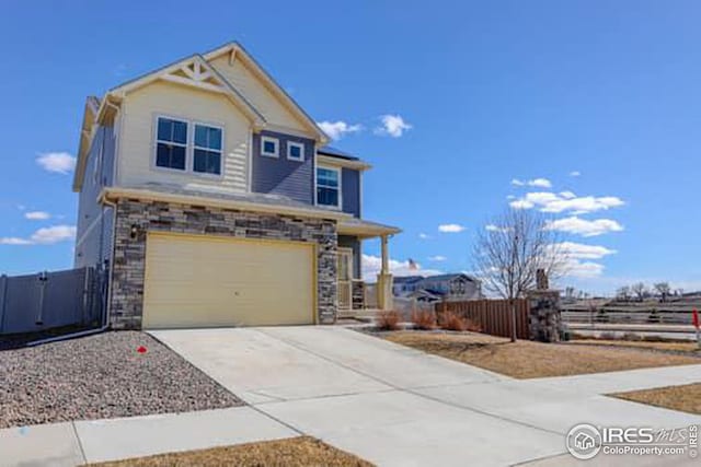 view of front of house with stone siding, fence, concrete driveway, and an attached garage