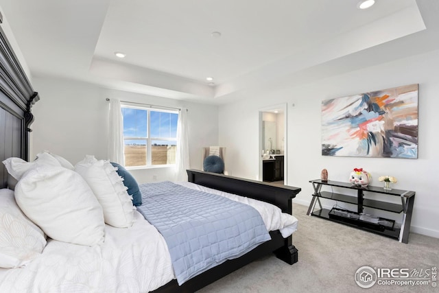 carpeted bedroom with baseboards, a tray ceiling, recessed lighting, and connected bathroom