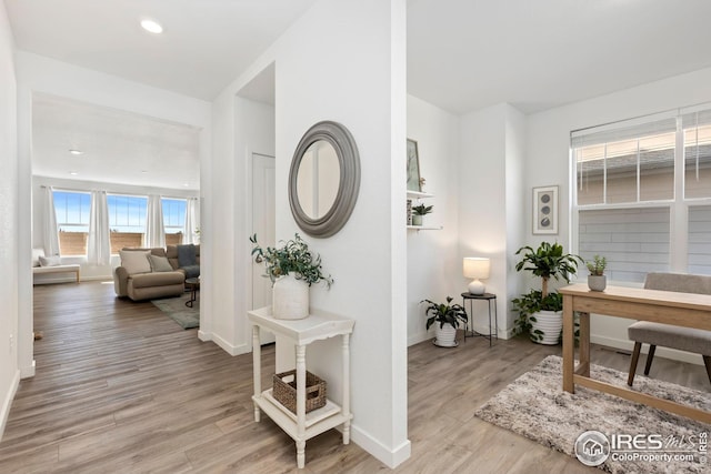 hallway featuring light wood finished floors, recessed lighting, and baseboards