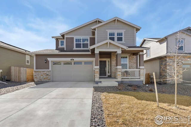 craftsman-style house featuring fence, driveway, covered porch, stone siding, and a garage