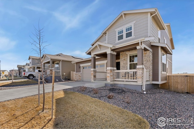 craftsman inspired home featuring driveway, stone siding, fence, a porch, and a garage