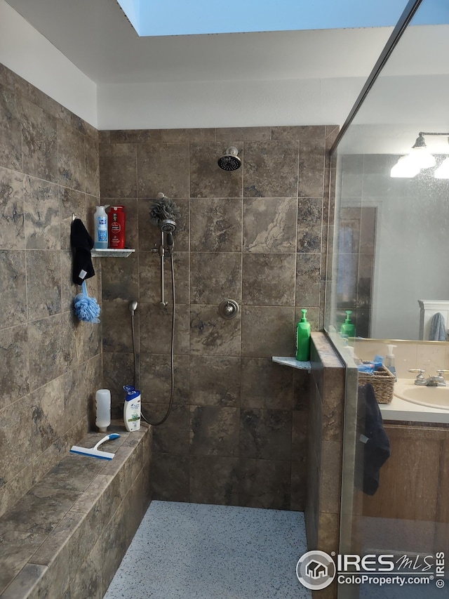 bathroom featuring a tile shower and vanity