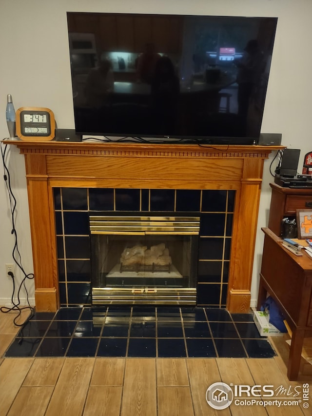 interior details featuring a tiled fireplace and wood finish floors