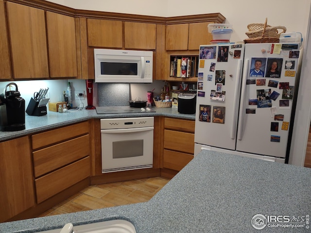 kitchen featuring white appliances, brown cabinetry, and light wood-type flooring