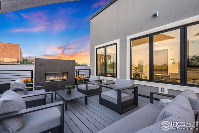 deck at dusk featuring an outdoor living space with a fireplace