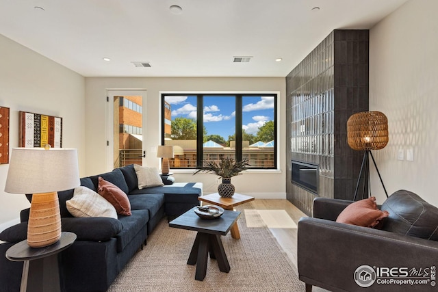 living area featuring wood finished floors, a tile fireplace, visible vents, and recessed lighting