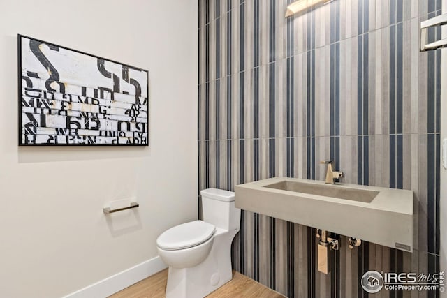 bathroom featuring toilet, a sink, baseboards, and wood finished floors