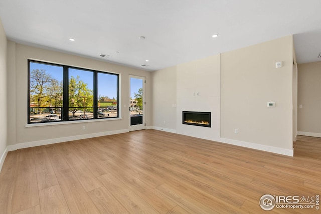 unfurnished living room with baseboards, visible vents, a tiled fireplace, light wood-type flooring, and recessed lighting