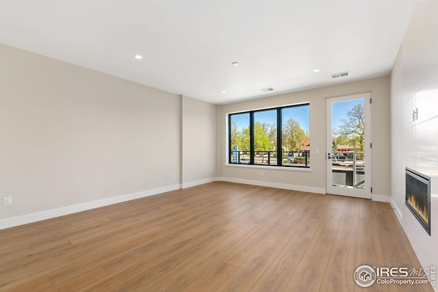 unfurnished living room with recessed lighting, visible vents, light wood-style flooring, a large fireplace, and baseboards