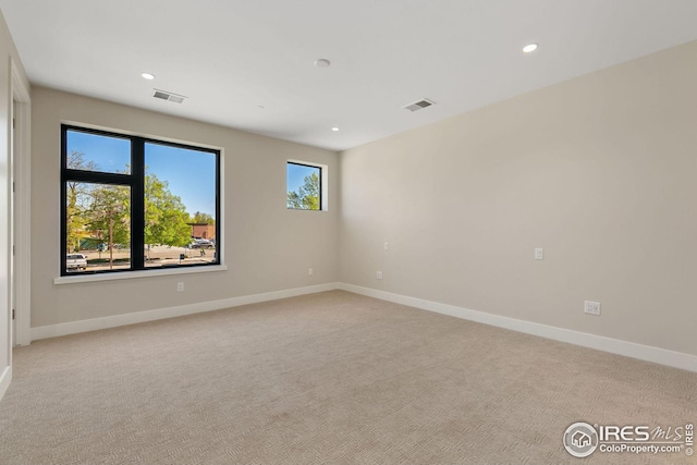 unfurnished room with recessed lighting, baseboards, visible vents, and light colored carpet