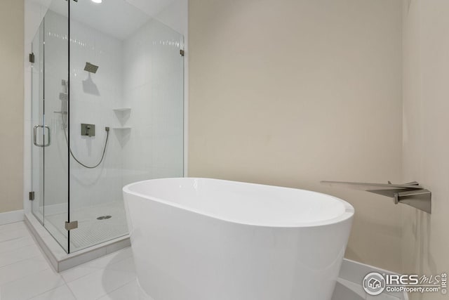 bathroom with tile patterned flooring, a shower stall, baseboards, and a freestanding bath