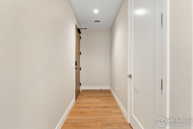 corridor featuring light wood-style flooring, visible vents, and baseboards