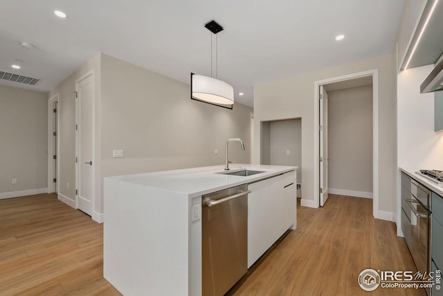 kitchen featuring light countertops, appliances with stainless steel finishes, light wood-style floors, white cabinets, and a sink