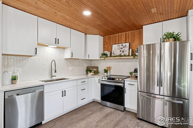 kitchen with light wood finished floors, wooden ceiling, appliances with stainless steel finishes, white cabinetry, and a sink