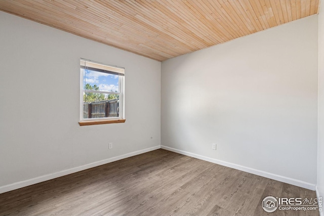 spare room featuring wooden ceiling, baseboards, and wood finished floors