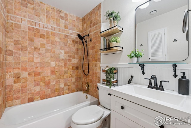 full bath featuring toilet, a wainscoted wall, vanity, and washtub / shower combination