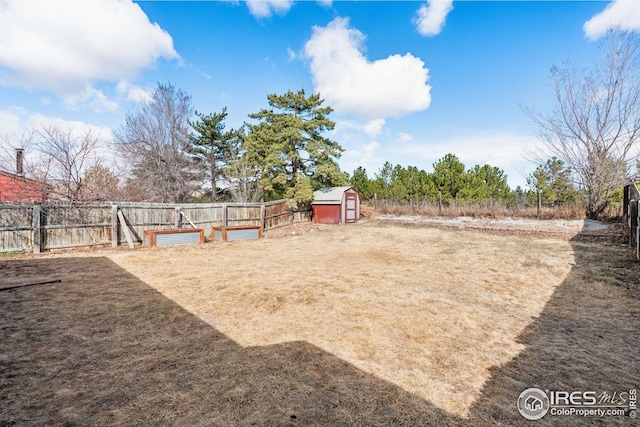 view of yard with an outbuilding, fence, and a storage shed