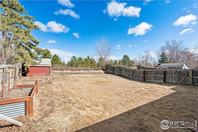 view of yard featuring a garden, an outbuilding, a fenced backyard, and a shed