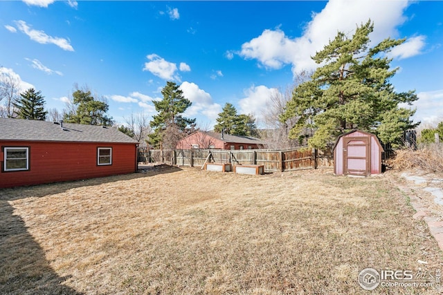 view of yard with fence, a storage unit, and an outbuilding