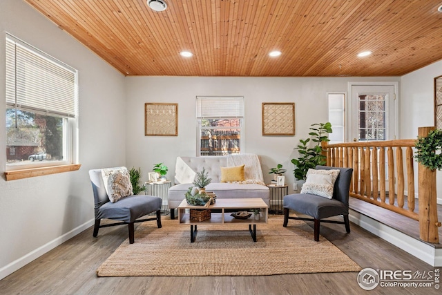 living area with plenty of natural light, wood ceiling, baseboards, and wood finished floors