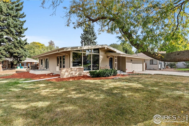 mid-century home featuring an attached garage, driveway, a front lawn, and brick siding