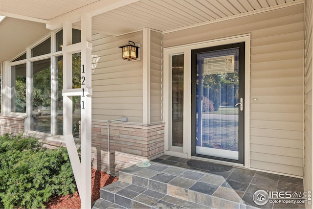 doorway to property featuring brick siding and a porch