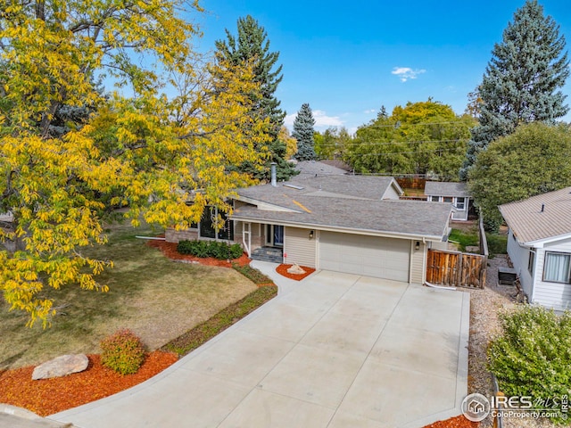 view of front of house with a shingled roof, a front yard, concrete driveway, and an attached garage