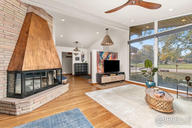 living area with recessed lighting, lofted ceiling with beams, ceiling fan, wood finished floors, and a multi sided fireplace