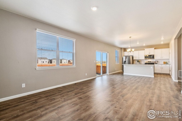 unfurnished living room featuring visible vents, baseboards, wood finished floors, an inviting chandelier, and recessed lighting