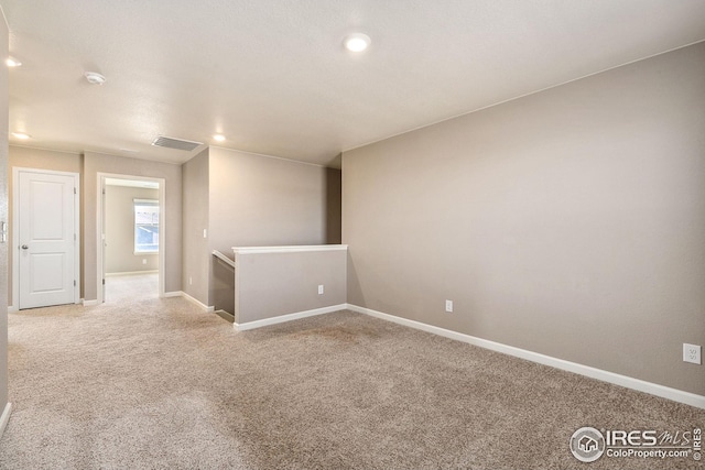 unfurnished room with light carpet, visible vents, and baseboards