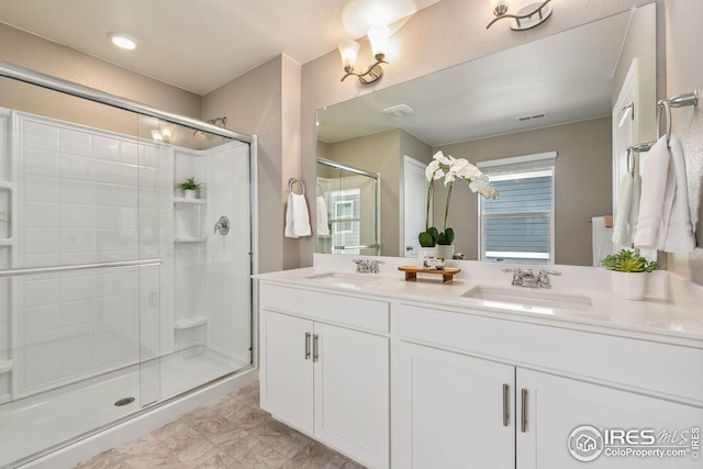 bathroom featuring visible vents, a sink, a shower stall, and double vanity