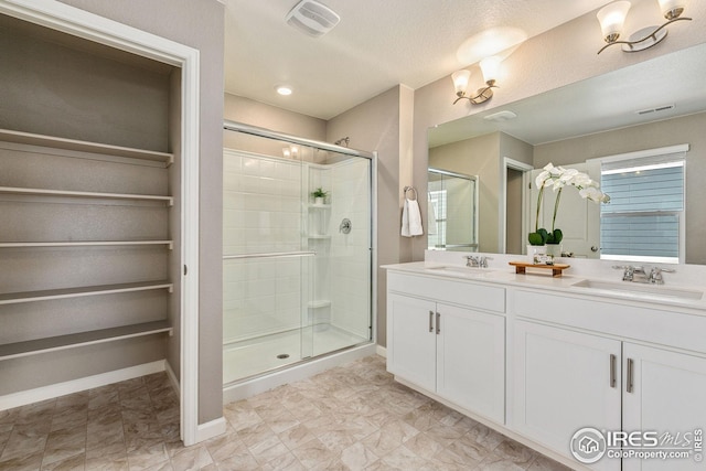 full bathroom with visible vents, a sink, and a shower stall