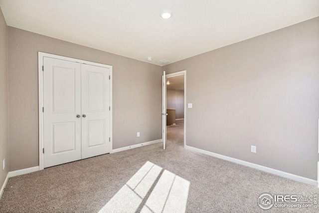 unfurnished bedroom with a closet, baseboards, and carpet flooring